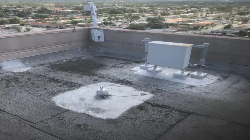 Aerial view of a flat rooftop with communication equipment and surrounding urban landscape.